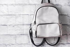 Shiny silver backpack on the background of a brick wall. Copy space photo