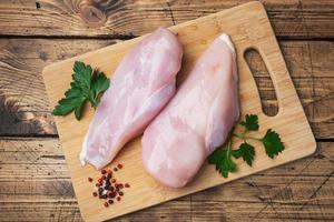 Raw chicken breast fillet on a wooden chopping board. Wooden rustic background. top view photo
