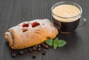 Coffee with bun on wooden background photo