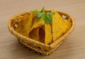 nachos en una canasta sobre fondo de madera foto