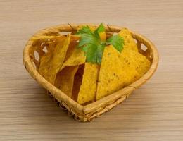 Nachos in a basket on wooden background photo