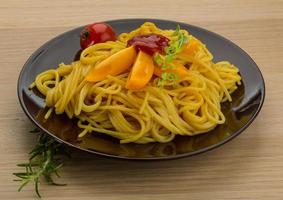 Vegetarian pasta on the plate and wooden background photo