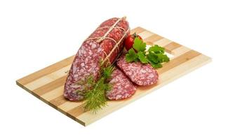 Salami on wooden plate and white background photo