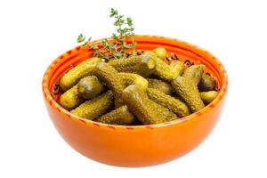 Marinated cucumbers in a bowl on white background photo