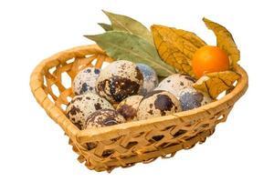 Quail eggs on wooden basket and white background photo