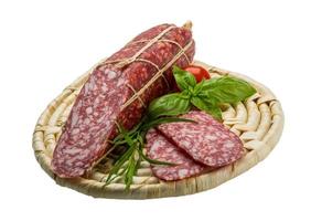 Salami on wooden plate and white background photo