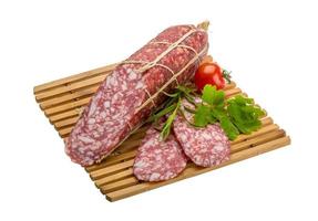 Salami on wooden plate and white background photo