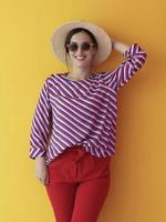 Portrait of young woman wearing sunglasses and hat over a yellow background photo