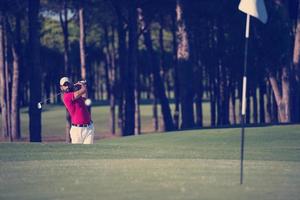 golfista golpeando un tiro de búnker de arena foto