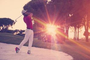 golfista golpeando un tiro de búnker de arena al atardecer foto