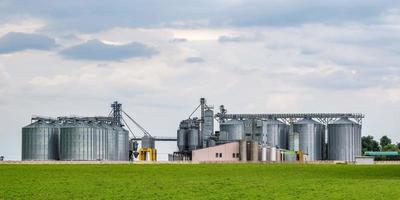 Modern Granary elevator and seed cleaning line. Silver silos on agro-processing and manufacturing plant for processing drying cleaning and storage of agricultural products, flour, cereals and grain. photo