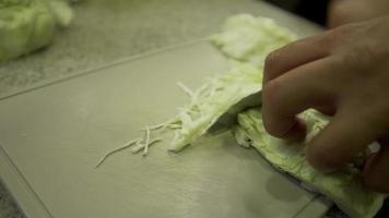 Slices slices of cabbage on a whiteboard. Grind thin slices with a sharp knife. video