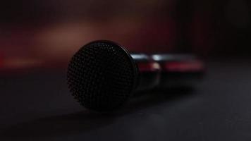 The microphone lies on the stage against the background of a concert show, performance or karaoke. Dynamic background color bokeh. The concept of a musical instrument