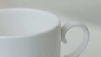 Cup of coffee on a white table with coffee beans. Stock video footage.