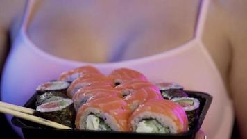 gros plan photo recadrée d'un homme tenant dans les mains un rouleau de sushi makizushi servi sur une assiette japonaise traditionnelle