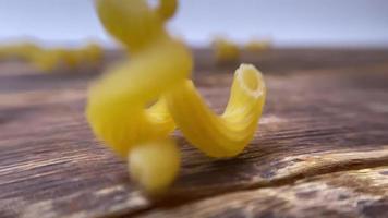 spirale pasta nel Marrone ciotola, sparpagliato pasta su di legno tavolo. superiore Visualizza video
