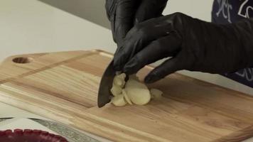 Close up of man cutting garlic on wooden board