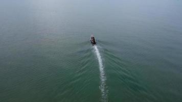 Luftaufnahme von einer Drohne traditioneller thailändischer Longtail-Fischerboote, die im Meer segeln. Draufsicht auf ein Fischerboot im Ozean.