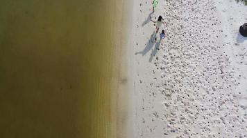 Aerial view from a drone of a happy Asian family of mother and daughters having fun playing on the beach during summer vacation. Summer family trip to the beach. travel and vacation concept.