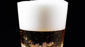 gira una jarra de cerveza sobre un fondo negro. cerveza pequeñas burbujas suben lentamente. video