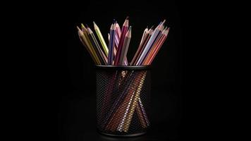 Colored pencils in metal pencil case rotating in the isolated dark ,black background. video