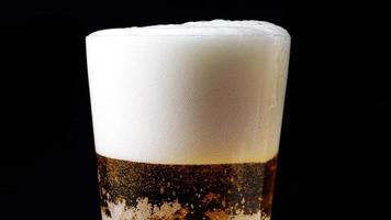 Glass of beer close up. A mug of beer on a black background rotates. beer small bubbles slowly rise. video