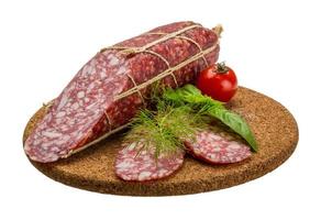 Salami on wooden plate and white background photo