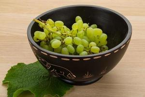 Green grapes in a bowl on wooden background photo