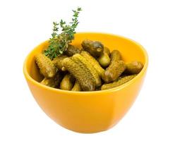 Marinated cucumbers in a bowl on white background photo