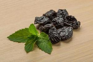 Dry plums on wooden background photo