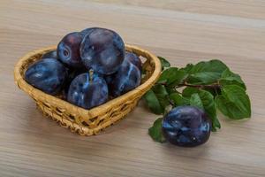 Fresh plums in a basket on white background photo