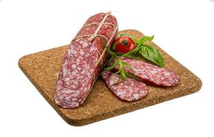 Salami on wooden plate and white background photo