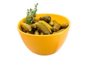 Marinated cucumbers in a bowl on white background photo