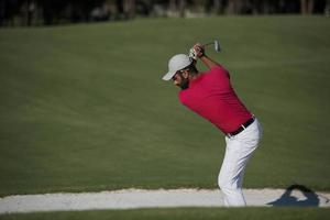 golfer hitting a sand bunker shot photo