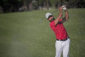 golfer hitting a sand bunker shot photo