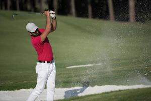 golfista golpeando un tiro de búnker de arena foto