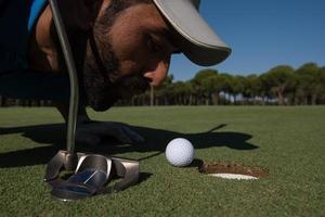 golf player blowing ball in hole photo