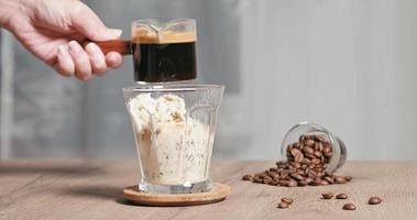 homemade Affogato is Italian dessert with coffee and scoop of gelato or vanilla ice cream into a cup. Then pour one shot of hot espresso. used hand pouring hot black coffee on ice cream in glass video