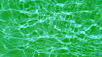 Defocus blurred transparent green colored clear calm water surface texture with splashes and bubbles. Trendy abstract nature background. Water waves in sunlight. Green water shining background. video