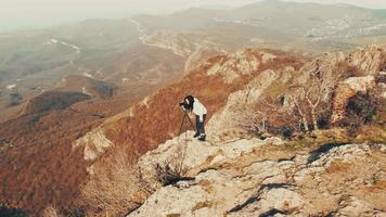 effectuer un zoom arrière jolie femme caucasienne photographiant dans les montagnes avec un appareil photo reflex numérique le matin.