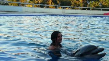 batumi, geórgia, 2022- garota com golfinho na piscina nadam juntos. batumi nadar com o conceito de experiência com golfinhos video