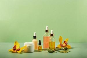 Cosmetic care products in glass bottles with orchid flowers - serums, cream, gel, oils. Concept for face and body care, wellness and spa, tropical relaxation. photo