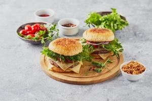 dos hamburguesas con chuleta de ternera y hierbas en tabla de cortar de madera foto