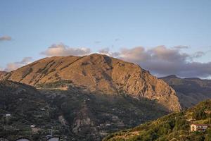 A big mountain with brown and green trees against a background of clear blue sky and copyspace. Huge rocky terrain perfect for hiking, rock climbing or scenic views of rugged outdoors. photo