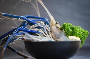 Fresh shrimp prawns with spices lemon green parsley for cooking Tom Yum Kung Thai food on dark background in the seafood restaurant - Raw shrimps on bowl photo