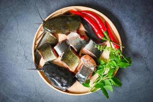 filete de bagre en plato de madera, menú de bagre crudo fresco pescado de agua dulce, bagre para cocinar, pescado picado con ingredientes hierbas y especias foto