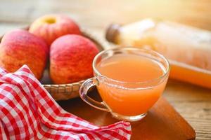 raw and unfiltered organic apple cider vinegar in glass with apple fruit on the wooden table, apple cider vinegar natural remedies and cures for common health condition photo
