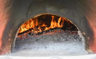 Chimenea con estufa de barro de leña de registro fuego en casa en el invierno - concepto de sala de chimenea foto