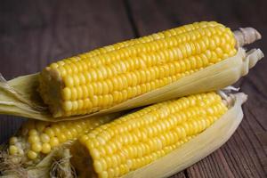 ripe corn cobs steamed or boiled sweetcorn for food vegan dinner or snack, cooked sweet corn on wooden background photo