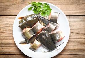 catfish fillet on white plate, fresh raw catfish menu freshwater fish, catfish for cooking food, fish chopped with ingredients coriander on wooden background